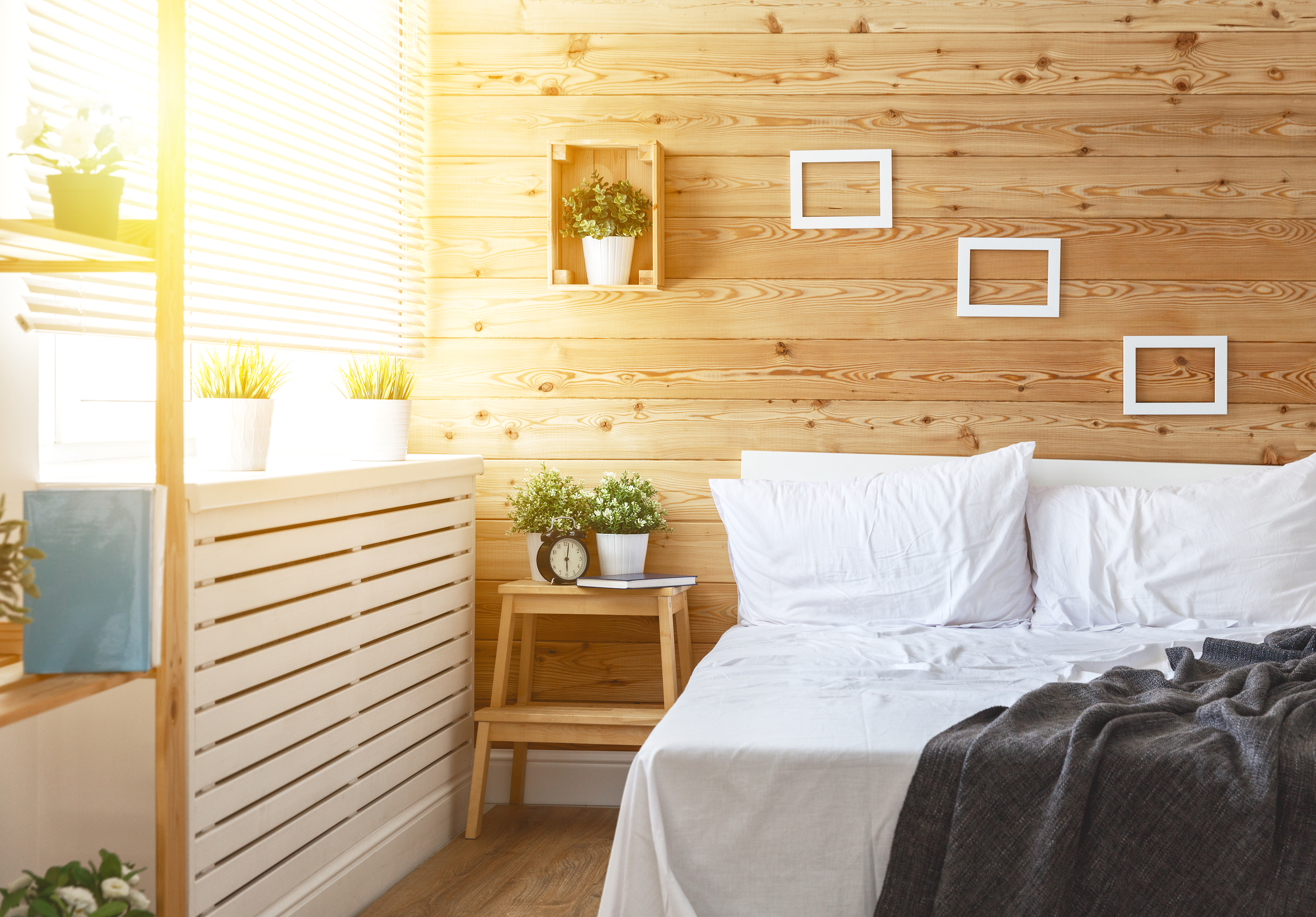 ściana na łóżkiem w sypialni ozdobiona drewnianymi deskami w jasnym kolorze