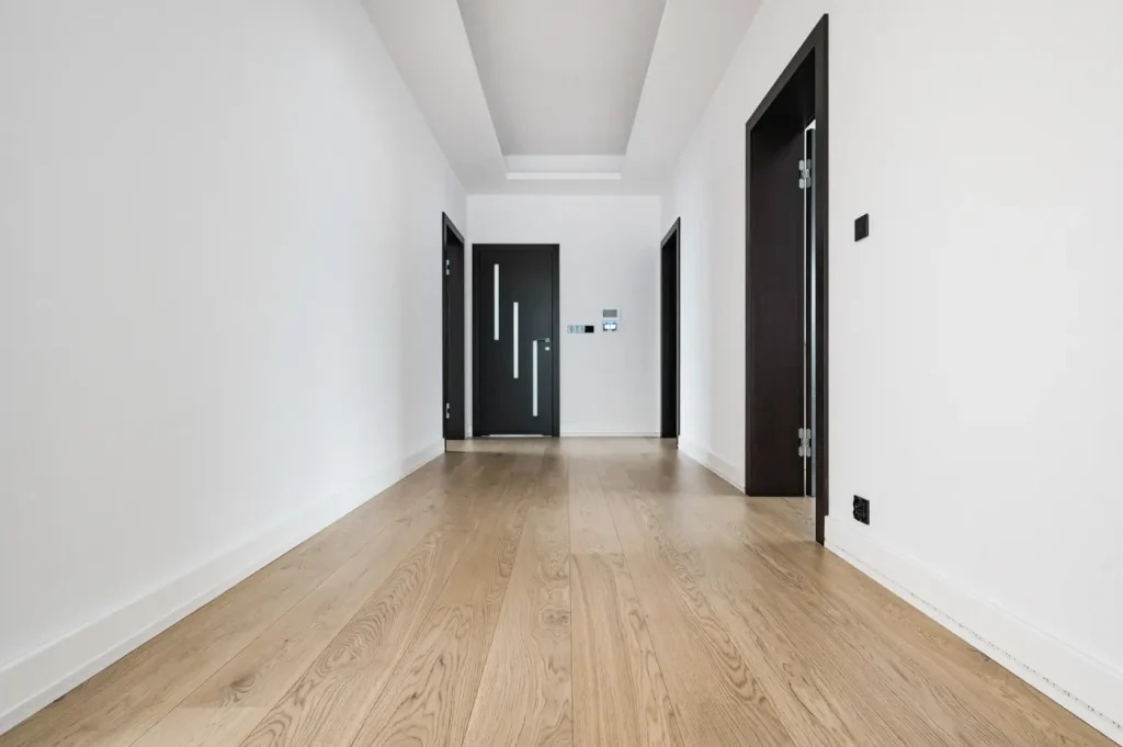Deska dębowa w naturalnym kolorze w korytarzu, ciemne drzwi do pokoi