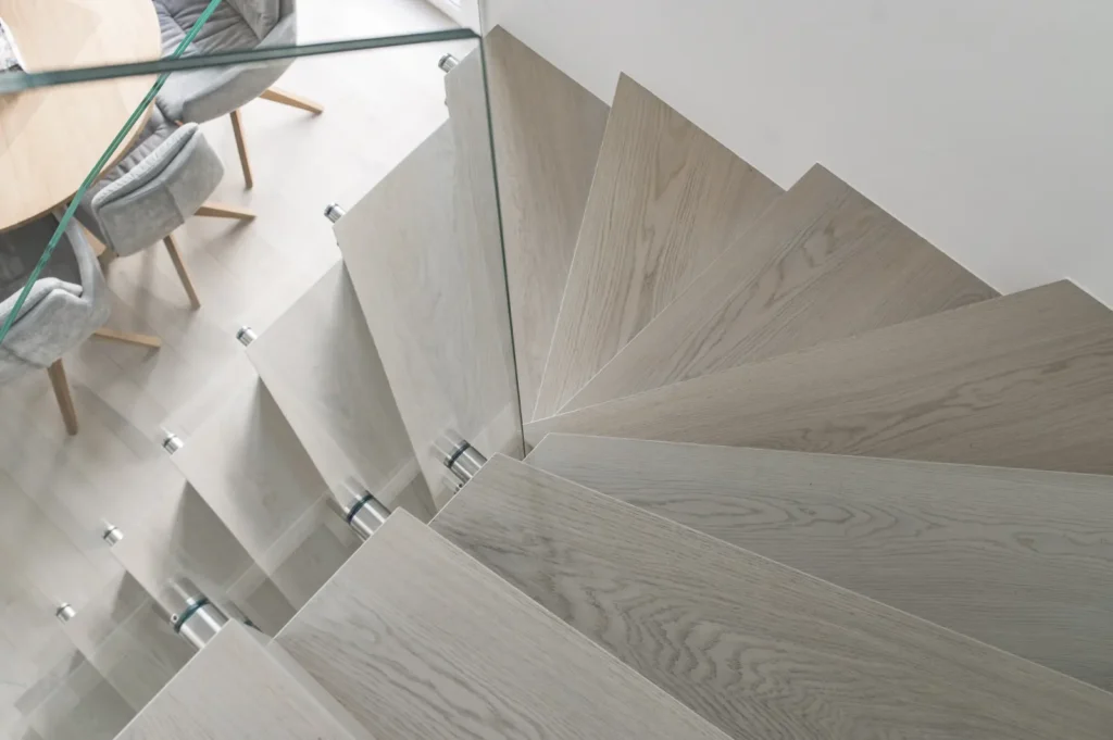 Schody dębowe bielone ze szklaną balustradą widziane z góry